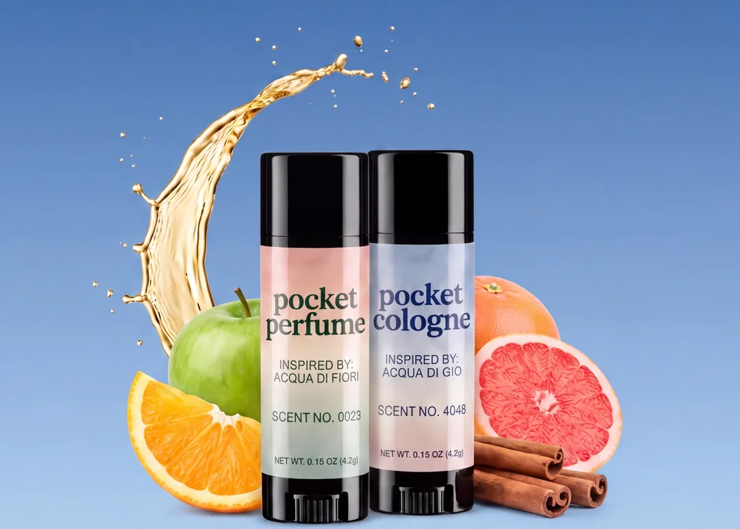 Pocket Perfume and Pocket Cologne sticks side by side, both labels facing forward, with fruit and a splash of fragrance oil behind them